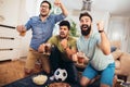 Male friends supporting football team at home