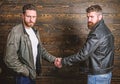 Male friendship concept. Brutal bearded men wear leather jackets shaking hands. Real men and brotherhood. Strong