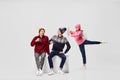 Cupid's arrow. Three young people in warm winter clothes sitting on big box isolated on gray background.