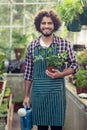 Male gardener holding potted plant and watering can Royalty Free Stock Photo