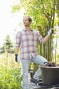 Male gardener looking away while standing at plant nursery