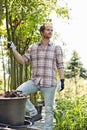 Male gardener looking away while standing at plant nursery