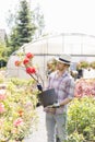 Male gardener looking at flower pot outside greenhouse