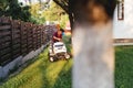 male gardner riding lawn mower and trimming grass in garden