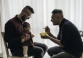 Male gay couple with adopted baby girl at home - Two handsome dads feed the baby girl on kitchen - Male babysitters - Lgbt family