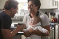 Male gay couple holding baby girl in their kitchen Royalty Free Stock Photo