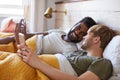 Male Gay Couple Lying In Bed At Home Checking Mobile Phones Together Royalty Free Stock Photo