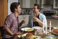 Male gay couple making a toast at dinner in their kitchen Royalty Free Stock Photo