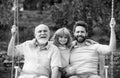 Male generation family together with three different generations ages grandfather father and son having fun on a swing Royalty Free Stock Photo