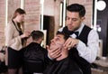 Male getting shave with straight razor in salon