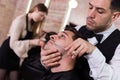 Male getting shave with straight razor in salon