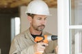 Male glazier using cordless drill to install windows