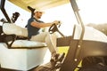 Male golfer driving a cart with golf clubs Royalty Free Stock Photo