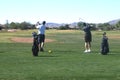 Male golfer hitting a golf ball from a back view.