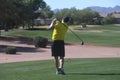 Male golfer hitting a golf ball from a back view.