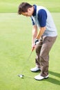Male golfer ready to putt the ball. Male golfer standing on the putting green and taking his position to putt the ball. Royalty Free Stock Photo