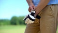 Male golfer wearing qualitative white glove, preparing to play, elite hobby