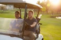 Male Golfers Driving Buggy Along Fairway Of Golf Course Royalty Free Stock Photo