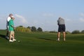 Male golfers on putting green.