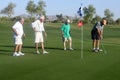 Male golfers on putting green.