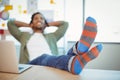 Male graphic designer relaxing with feet up at desk