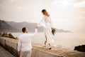 Male groom and female bride with a bouquet walking on the bridge holding hands Royalty Free Stock Photo