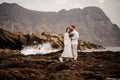 Male groom and female bride standing on the rocky beach with the bouquet Royalty Free Stock Photo