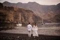 Male groom and female bride standing on the rocky beach looking at yacht Royalty Free Stock Photo