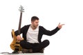 Male guitarist sitting on the floor and pointing Royalty Free Stock Photo