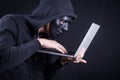 Male hacker with black mask carrying laptop Royalty Free Stock Photo