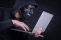 Male hacker with black mask carrying laptop