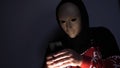 Male hacker hidden face with the mask accessing to personal information on laptop phone in the dark. Technology, cyber crime con