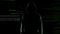 Male hacker silhouette in hoodie standing in front of animated computer code
