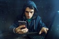 Male hacker uses the mobile phone to hack the system. Concept of cyber crime and hacking electronic devices