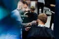 Male haircut with electric razor. Tattooed Barber makes haircut for client at the barber shop by using hairclipper. Man Royalty Free Stock Photo