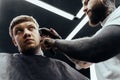 Male haircut with electric razor. Tattooed Barber makes haircut for client at the barber shop by using hairclipper. Man Royalty Free Stock Photo