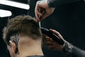 Male haircut with electric razor. Tattooed Barber makes haircut for client at the barber shop by using hairclipper. Man Royalty Free Stock Photo