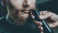 A male hairdresser does a haircut of a beard and a mustache