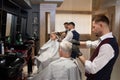 Male hairdressers grooming client`s haircuts in barbershop. Royalty Free Stock Photo