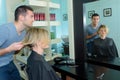 Male hairstylist making haircut for happy woman Royalty Free Stock Photo