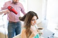 Woman Drinking Coffee While Stylist Drying Hair Royalty Free Stock Photo