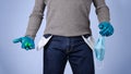 Male half body view. Protected man with gloves and surgical mask, shows the pockets of his empty pants. Concept of crisis and Royalty Free Stock Photo