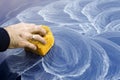 Male hand applies polishing paste on car paint with sponge