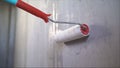 A worker applies a primer to the wall with a long roller. A male hand is applying a primer to a white wall with a roller. Wet Royalty Free Stock Photo