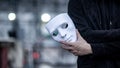 Male hand of black jacket man holding white mask. Anonymous social masking or major depressive disorder concept Royalty Free Stock Photo