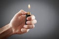 Male hand burning lighter in grey background Royalty Free Stock Photo