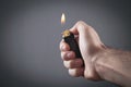 Male hand burning lighter in grey background Royalty Free Stock Photo