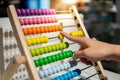 Male hand calculating beads on rainbow abacus