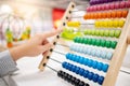 Male hand calculating beads on rainbow abacus