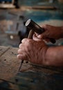 Male hand carpenter at work carving wood using a woodworking tool in a cottage